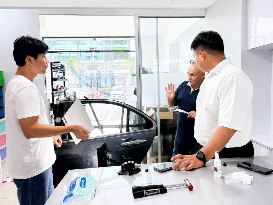 M&H Group trainer explains a PDR repair exercise beside a vehicle door and professional tools