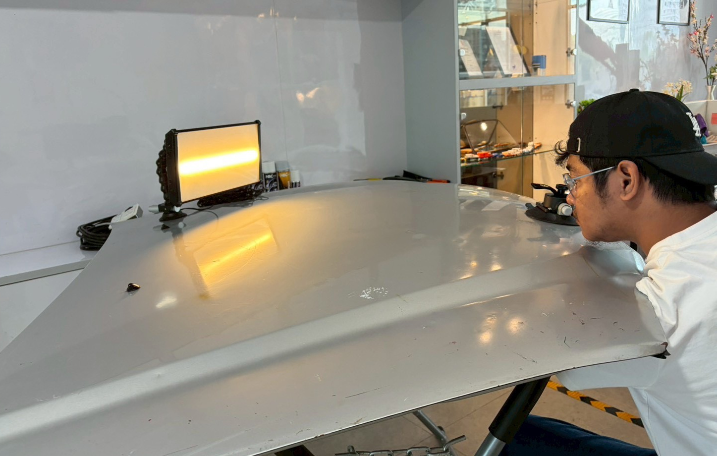 View B: the observer's eye is closer to panel height. From this lower camera view, the warm reflected band appears in a different position and shape. The photograph alone does not establish a repair change.